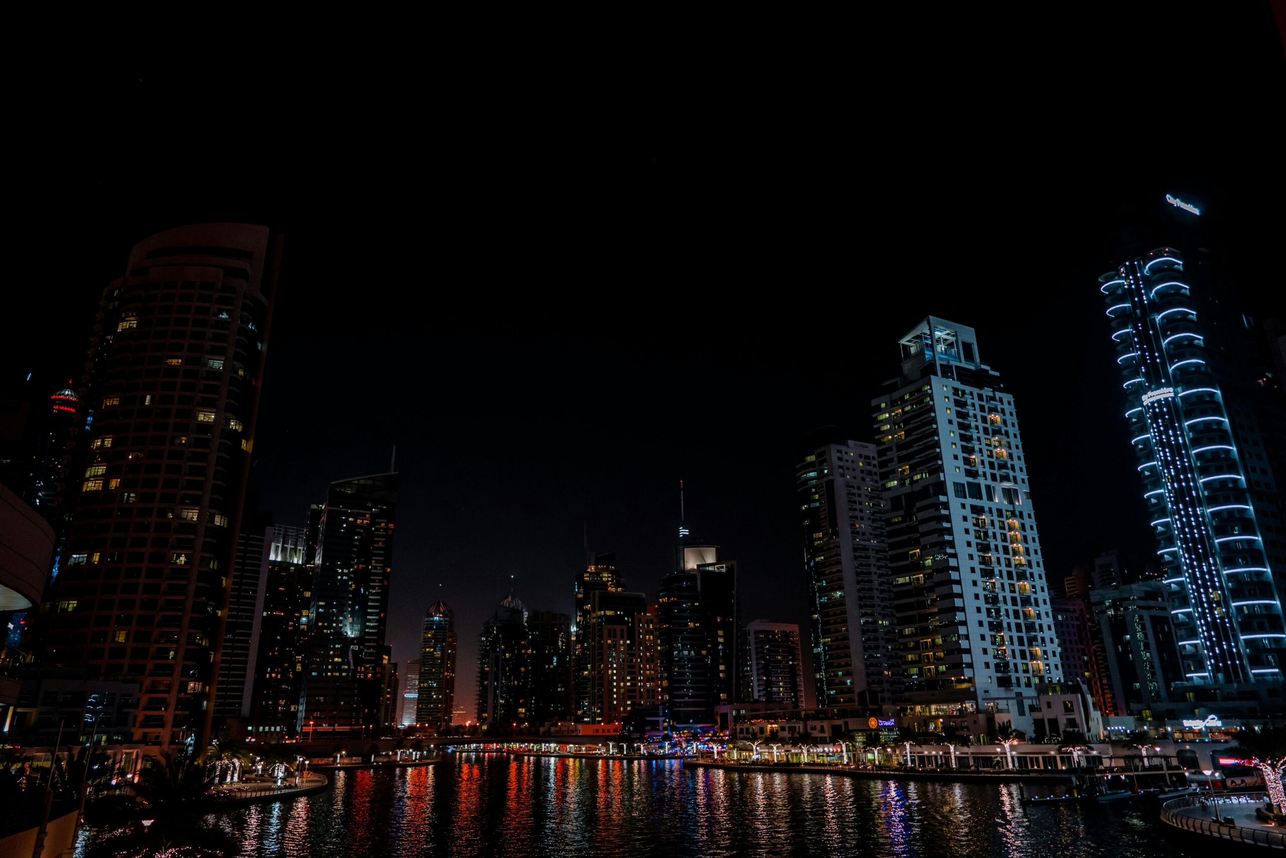 Stunning night view of Dubai Marina with illuminated skyscrapers reflecting on the water.